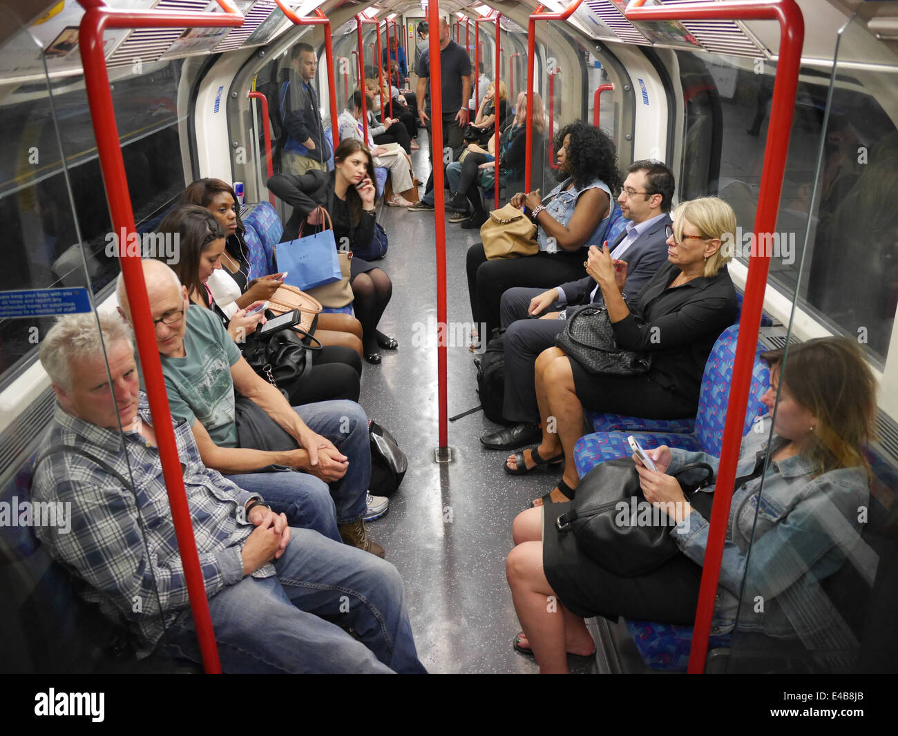 Passengers using mobile phones and tablets on tube train on London