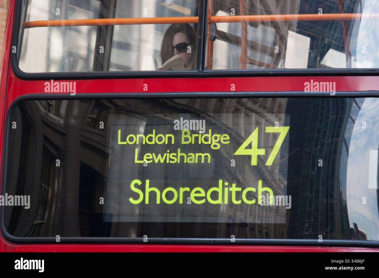 young female reading book on 47 red london Arriva bus with London Bridge Lewisham and Shoreditch on destination sign Stock Photo