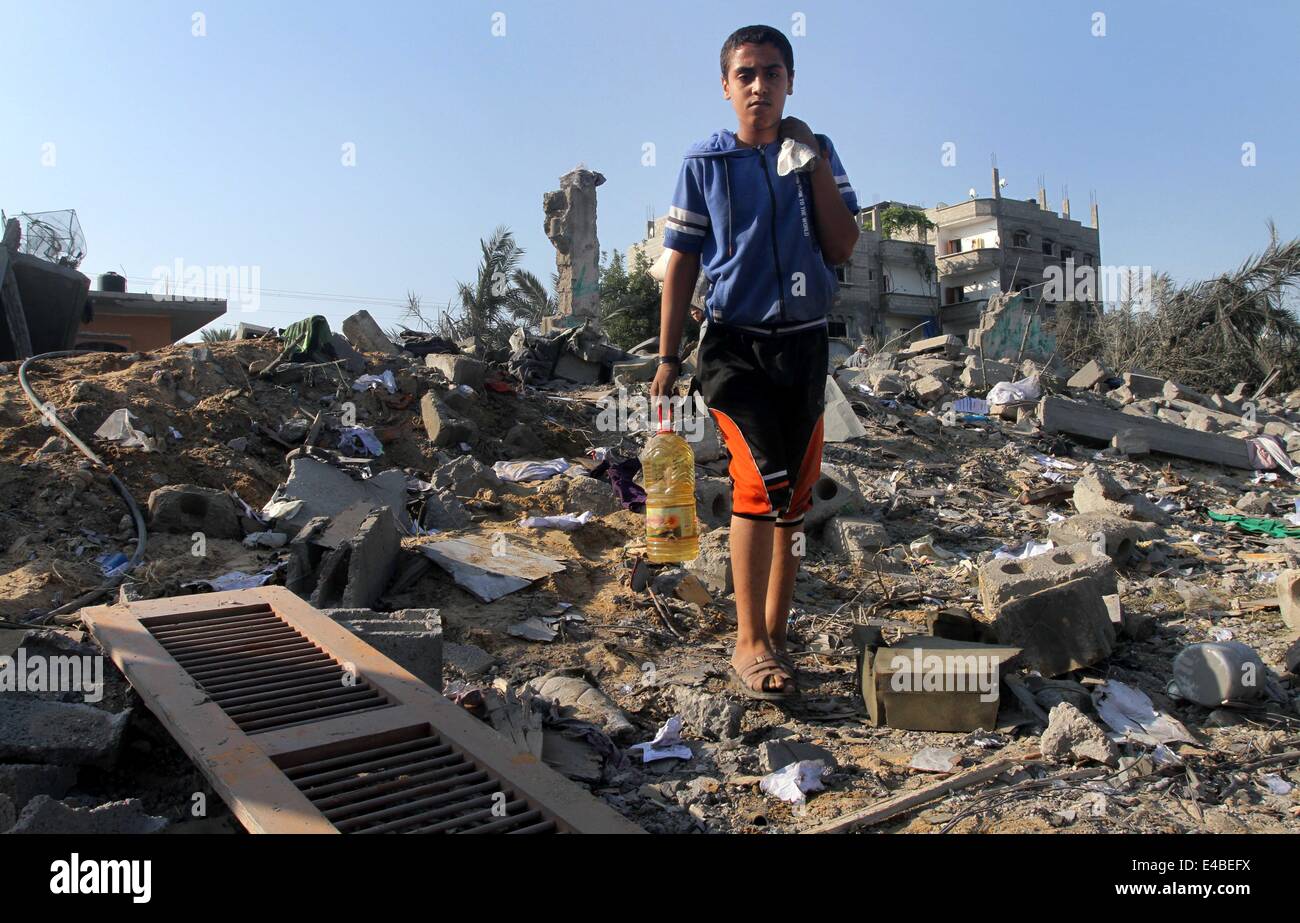 April 16, 2010 - Khan Younis, Gaza Strip, Palestinian Territory - A Palestinian boy carries belongings from a house which police said was destroyed in an Israeli air strike, and which a neighbour identified as belonging to a Hamas member, in Khan Younis in the southern Gaza Strip July 8, 2014. Israel launched an offensive against Islamist Hamas in the Gaza Strip on Tuesday, bombing some 50 targets, including homes, in a campaign meant to end Palestinian rocket fire into the Jewish state. The Israeli military said it targeted about 50 sites in aerial and naval assaults. Palestinian officials sa Stock Photo