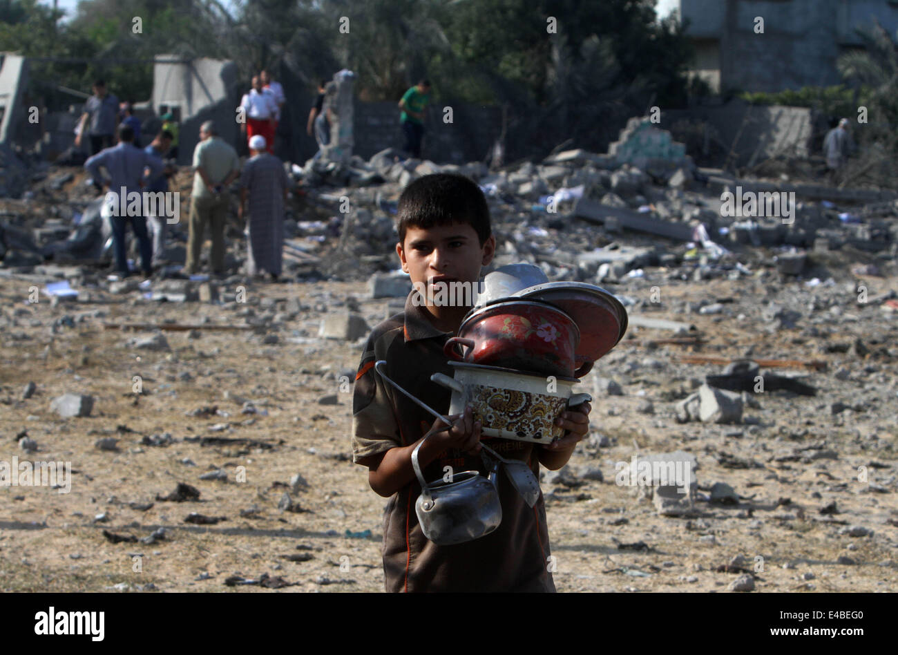 April 16, 2010 - Khan Younis, Gaza Strip, Palestinian Territory - A Palestinian boy carries belongings from a house which police said was destroyed in an Israeli air strike, and which a neighbour identified as belonging to a Hamas member, in Khan Younis in the southern Gaza Strip July 8, 2014. Israel launched an offensive against Islamist Hamas in the Gaza Strip on Tuesday, bombing some 50 targets, including homes, in a campaign meant to end Palestinian rocket fire into the Jewish state. The Israeli military said it targeted about 50 sites in aerial and naval assaults. Palestinian officials sa Stock Photo