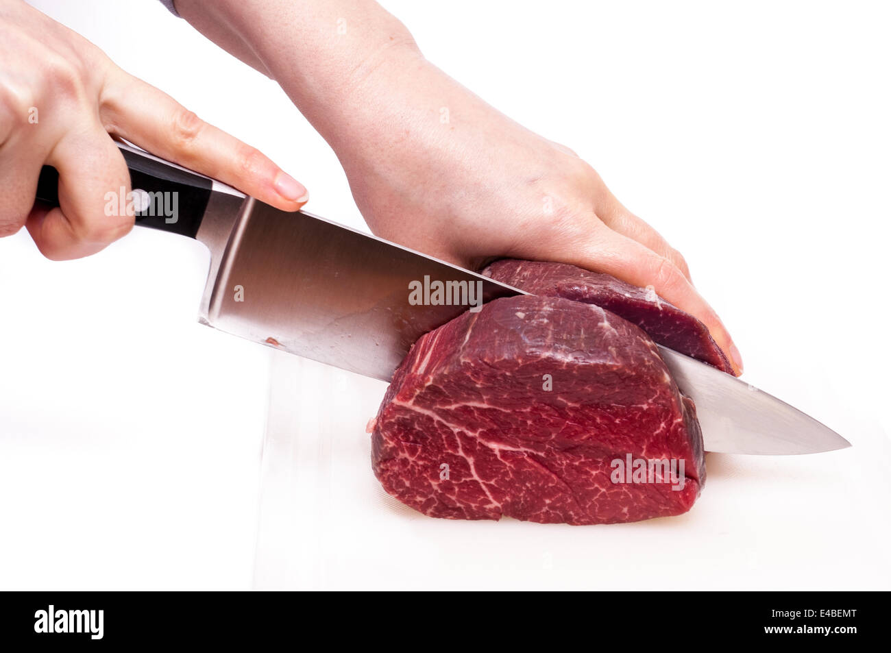 Two hands cutting a fillet of beef Stock Photo