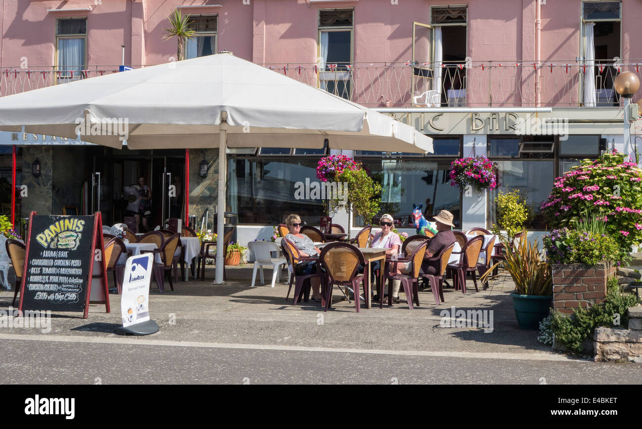 People sitting outside a restaurant at the seaside, relaxing in summer, England, UK Stock Photo