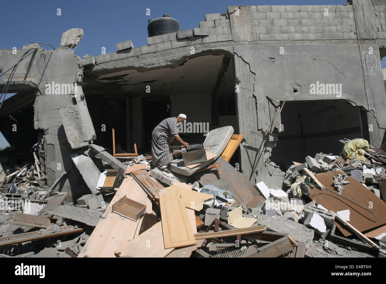 Khan Younis, Gaza Strip, Palestinian Territory. 8th July, 2014. A Palestinian man inspects a house which police said was destroyed in an Israeli air strike in Khan Younis in the southern Gaza Strip July 8, 2014. Israel launched an offensive against Islamist Hamas in the Gaza Strip on Tuesday, bombing some 50 targets, including homes, in a campaign meant to end Palestinian rocket fire into the Jewish state. The Israeli military said it targeted about 50 sites in aerial and naval assaults. Credit:  ZUMA Press, Inc./Alamy Live News Stock Photo