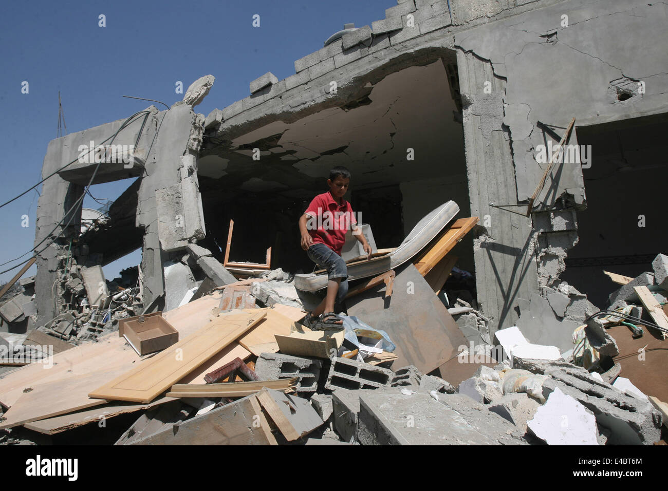 Khan Younis, Gaza Strip, Palestinian Territory. 8th July, 2014. A Palestinian boy inspects a house which police said was destroyed in an Israeli air strike in Khan Younis in the southern Gaza Strip July 8, 2014. Israel launched an offensive against Islamist Hamas in the Gaza Strip on Tuesday, bombing some 50 targets, including homes, in a campaign meant to end Palestinian rocket fire into the Jewish state. The Israeli military said it targeted about 50 sites in aerial and naval assaults. Credit:  ZUMA Press, Inc./Alamy Live News Stock Photo