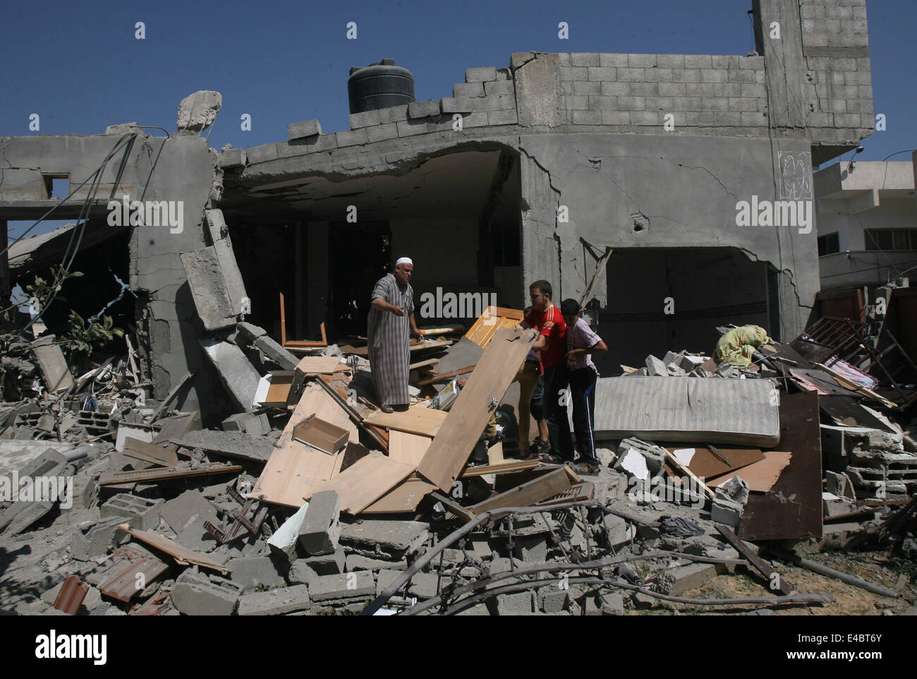 Khan Younis, Gaza Strip, Palestinian Territory. 8th July, 2014. Palestinians inspect a house which police said was destroyed in an Israeli air strike in Khan Younis in the southern Gaza Strip July 8, 2014. Israel launched an offensive against Islamist Hamas in the Gaza Strip on Tuesday, bombing some 50 targets, including homes, in a campaign meant to end Palestinian rocket fire into the Jewish state. The Israeli military said it targeted about 50 sites in aerial and naval assaults. Credit:  ZUMA Press, Inc./Alamy Live News Stock Photo