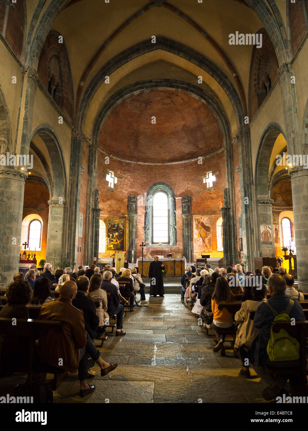 Clergyman and people in the monastery church of Sacra di San Michele in the Susa Valley, Italy. Stock Photo