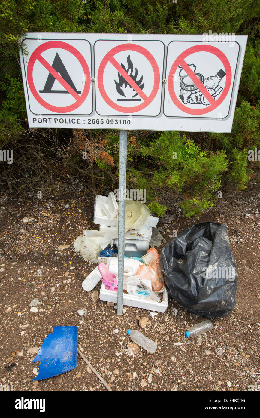 The irony of litter dumped next to a no littering sign on an island off Sivota, Greece. Stock Photo