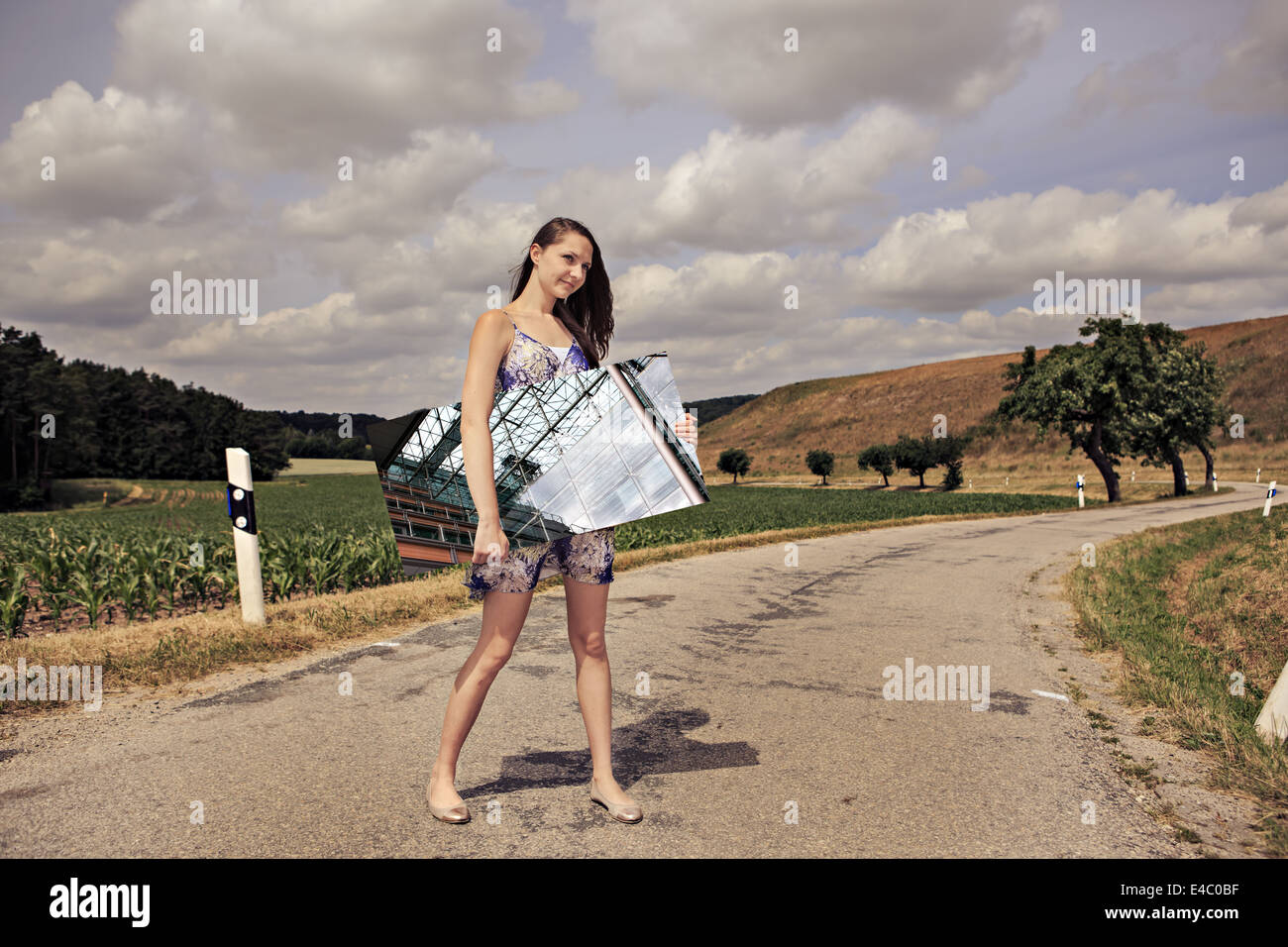 outdoor portrait of a young girl with a mirror in front of rural landscape Stock Photo