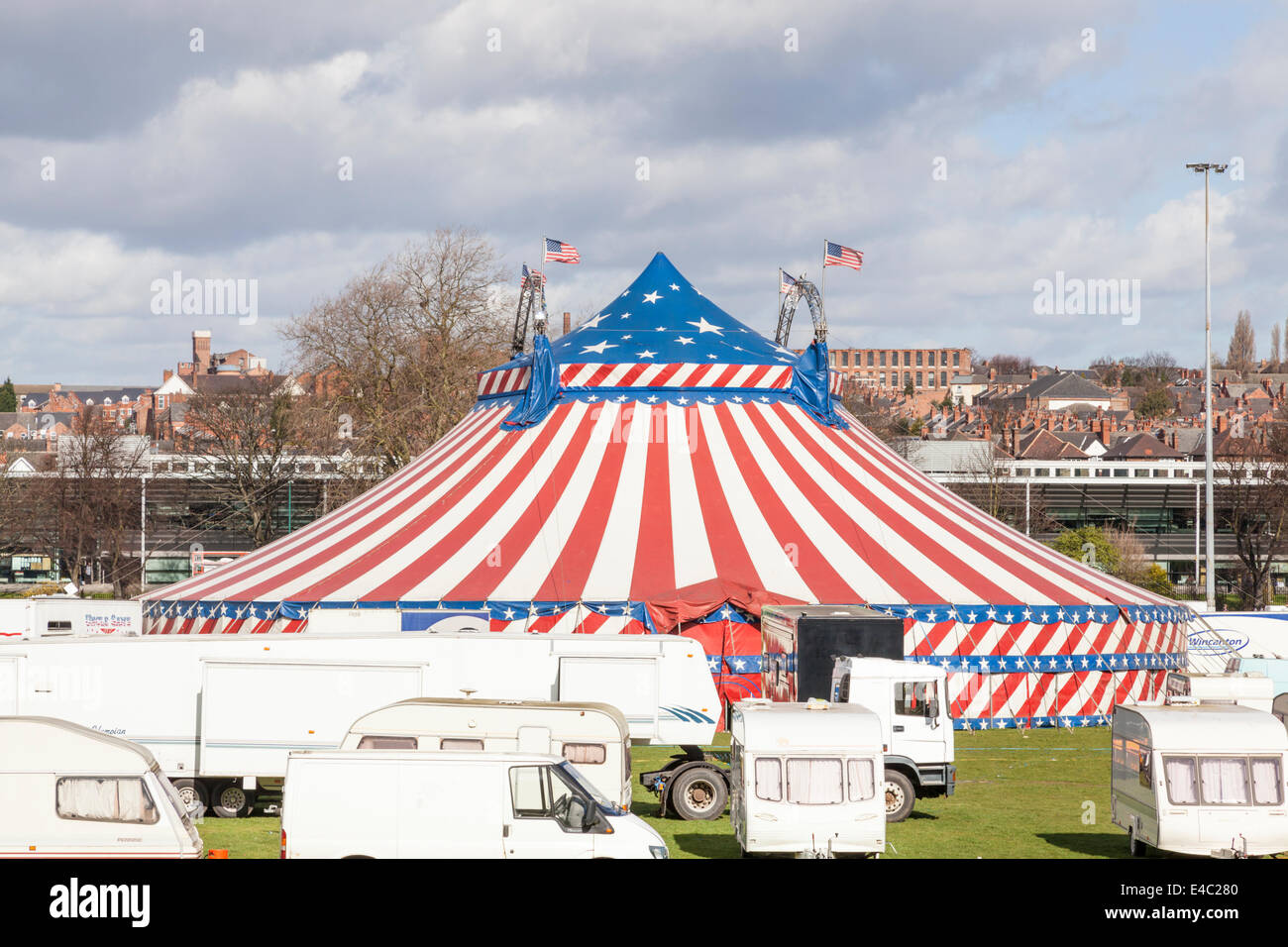Uncle Sam's American Circus big top and vehicles in a city park with housing in the distance. Nottingham, England, UK Stock Photo