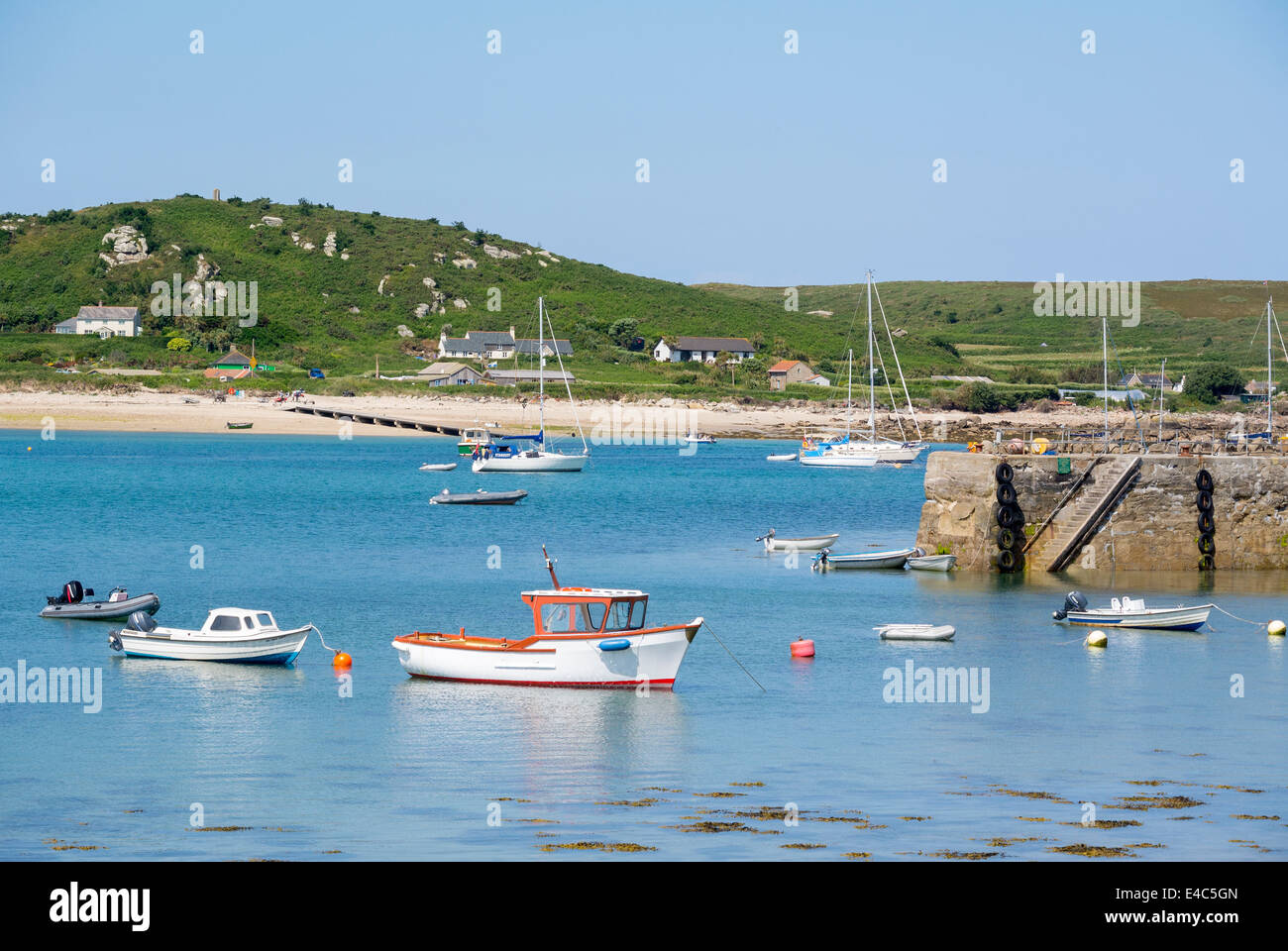 Tresco isles of Scilly New Grimsby harbour boats and quay with Bryher island in the background, Cornwall England UK. Stock Photo