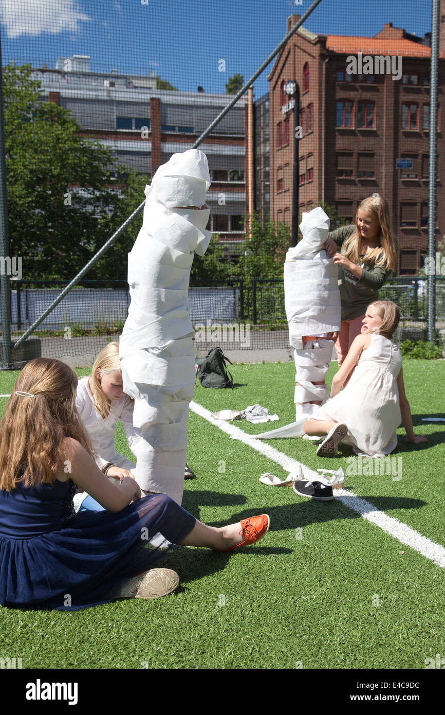Children playing a game wrapping a team member up using toilet roll Stock Photo Alamy
