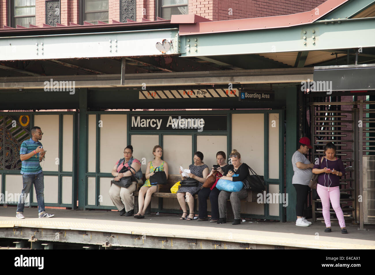 Subway riders wait for an M Train to Manhattan at the Marcy Ave