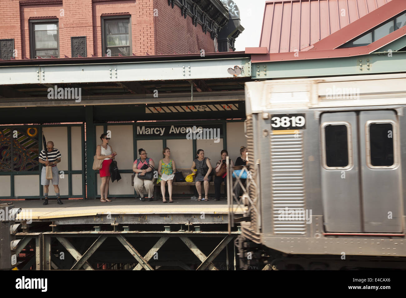 Subway riders wait for an M Train to Manhattan at the Marcy Ave