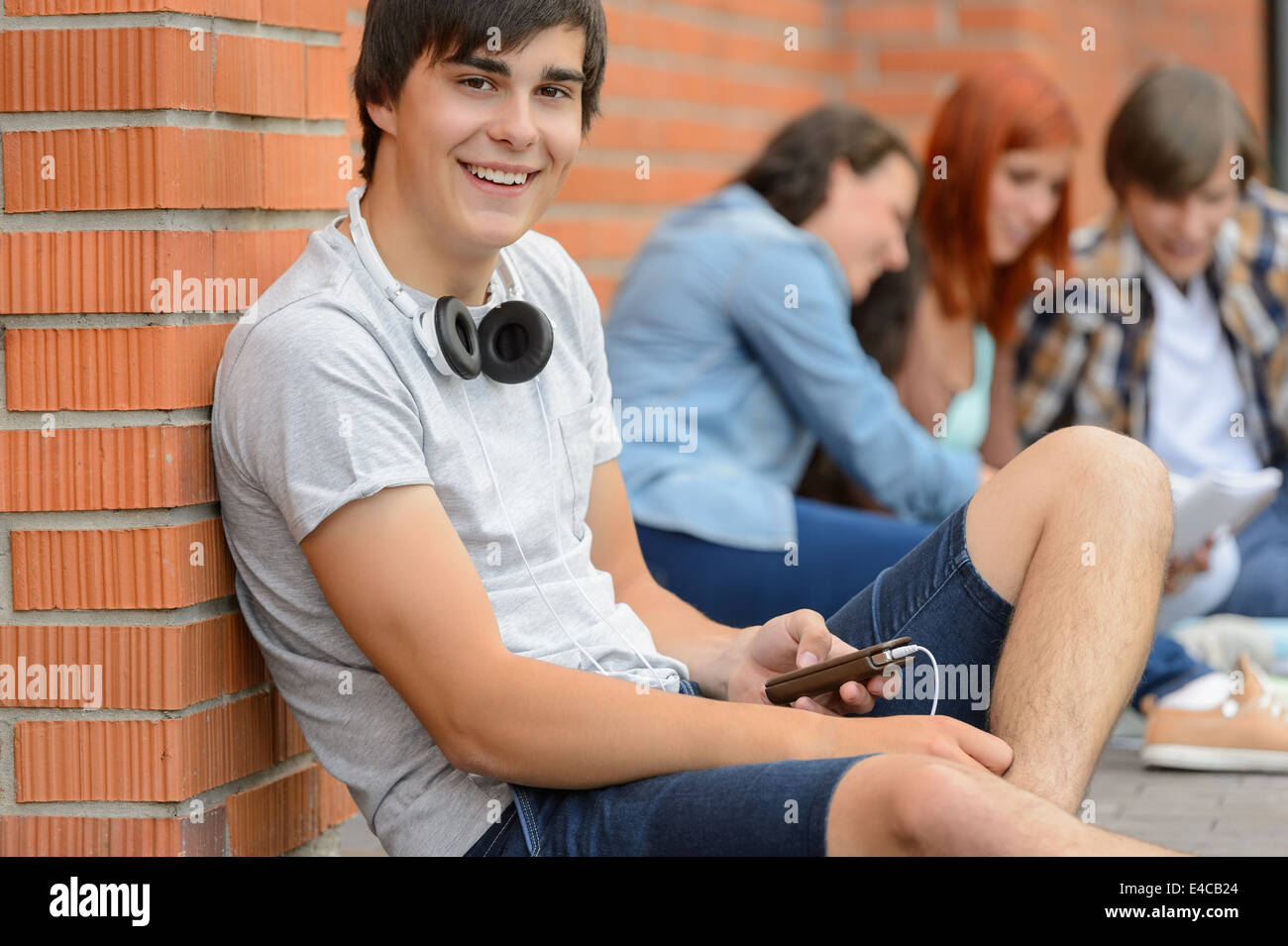College student boy sitting on ground with friends hanging out Stock Photo
