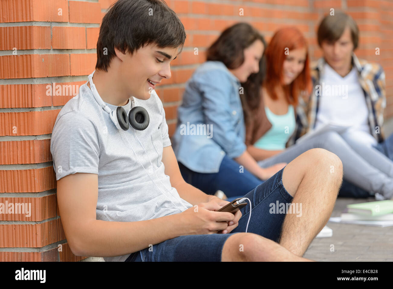 Young student man hanging out with college friends sitting ground Stock Photo