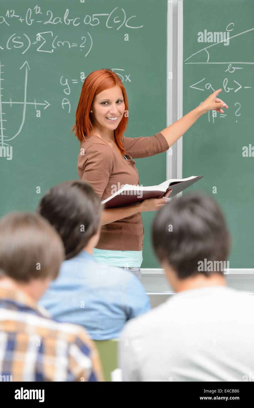 Mathematics student girl pointing on chalkboard looking at classmates Stock Photo