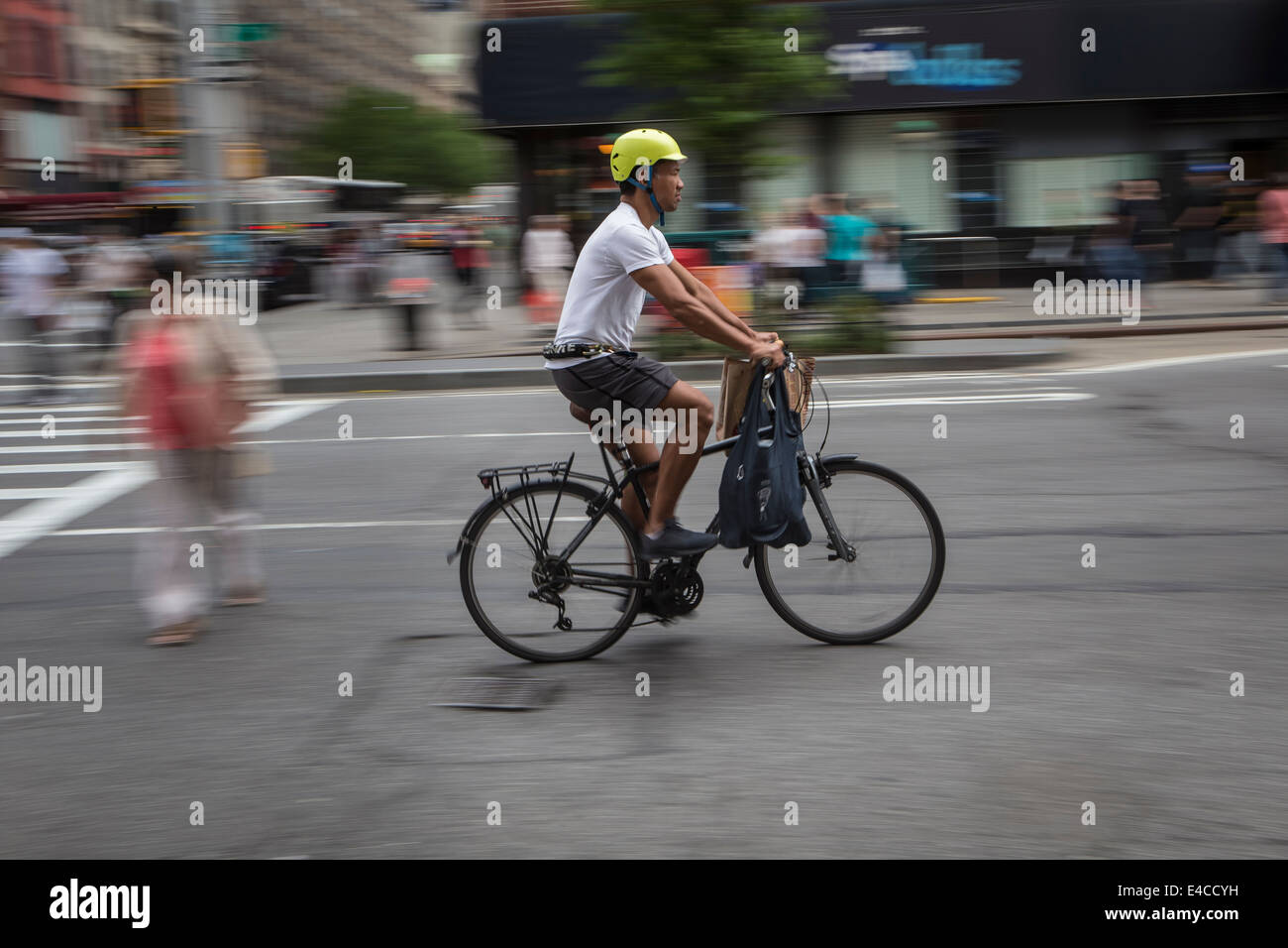 A man rides a bike on a busy street in the New York City borough of Manhattan, NY Stock Photo