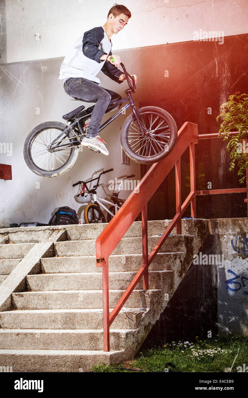 BMX biker performing a stunt on a staircase railing Stock Photo