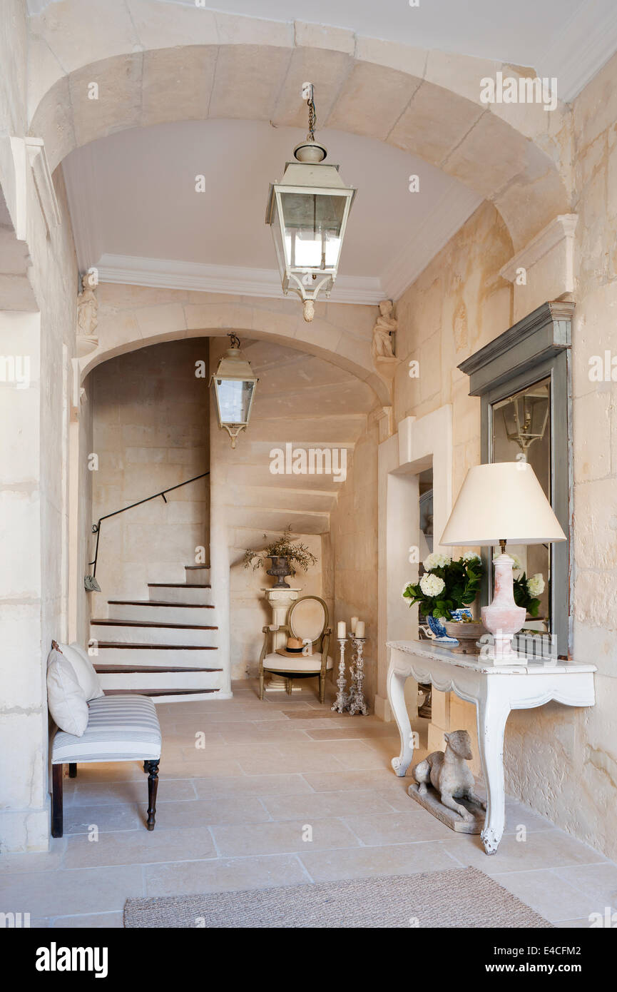 Entrance hall in 18th century provencal house with stone staircase and antique two legged wooden console table Stock Photo