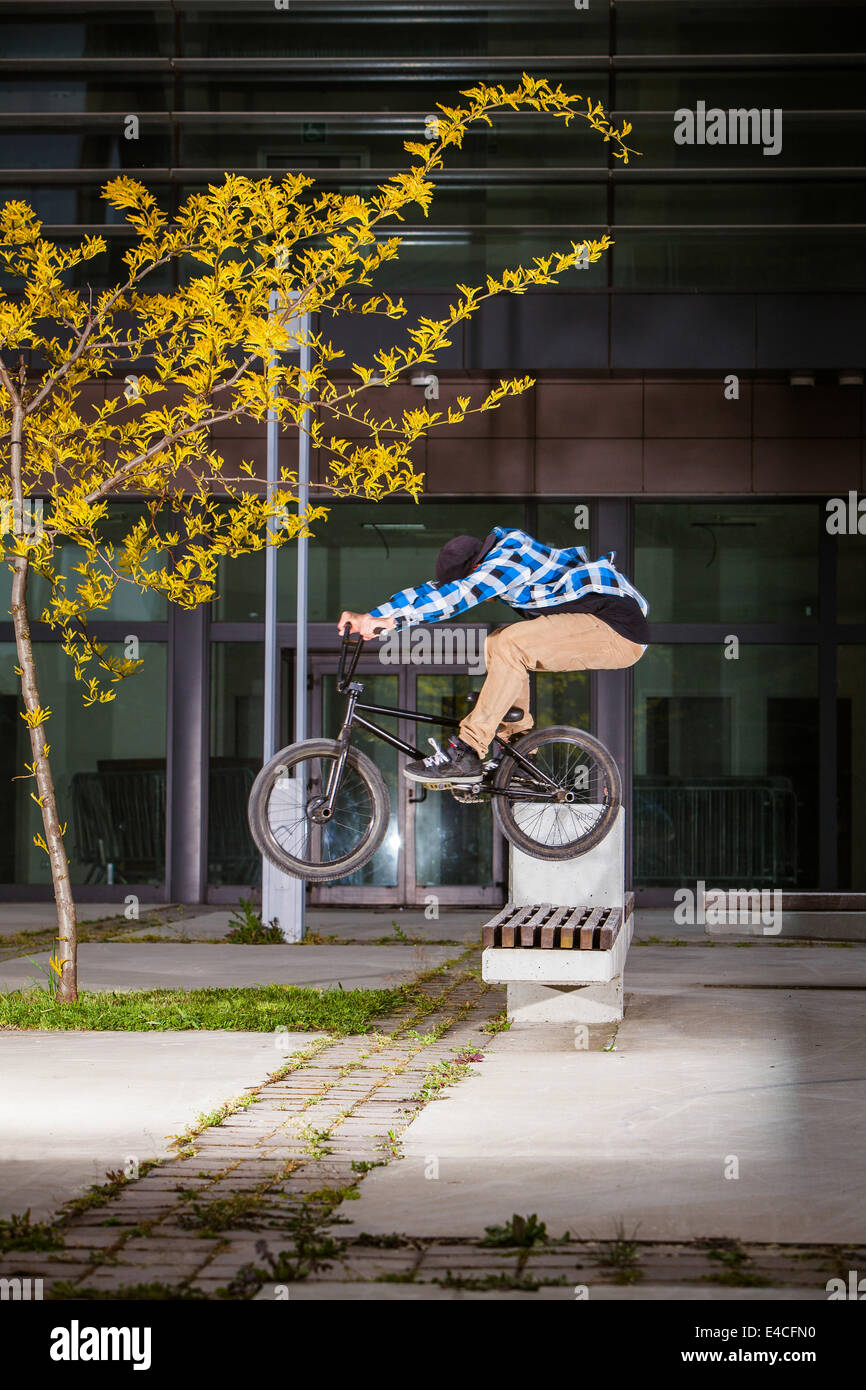 BMX biker performing a stunt on the sidewalk Stock Photo