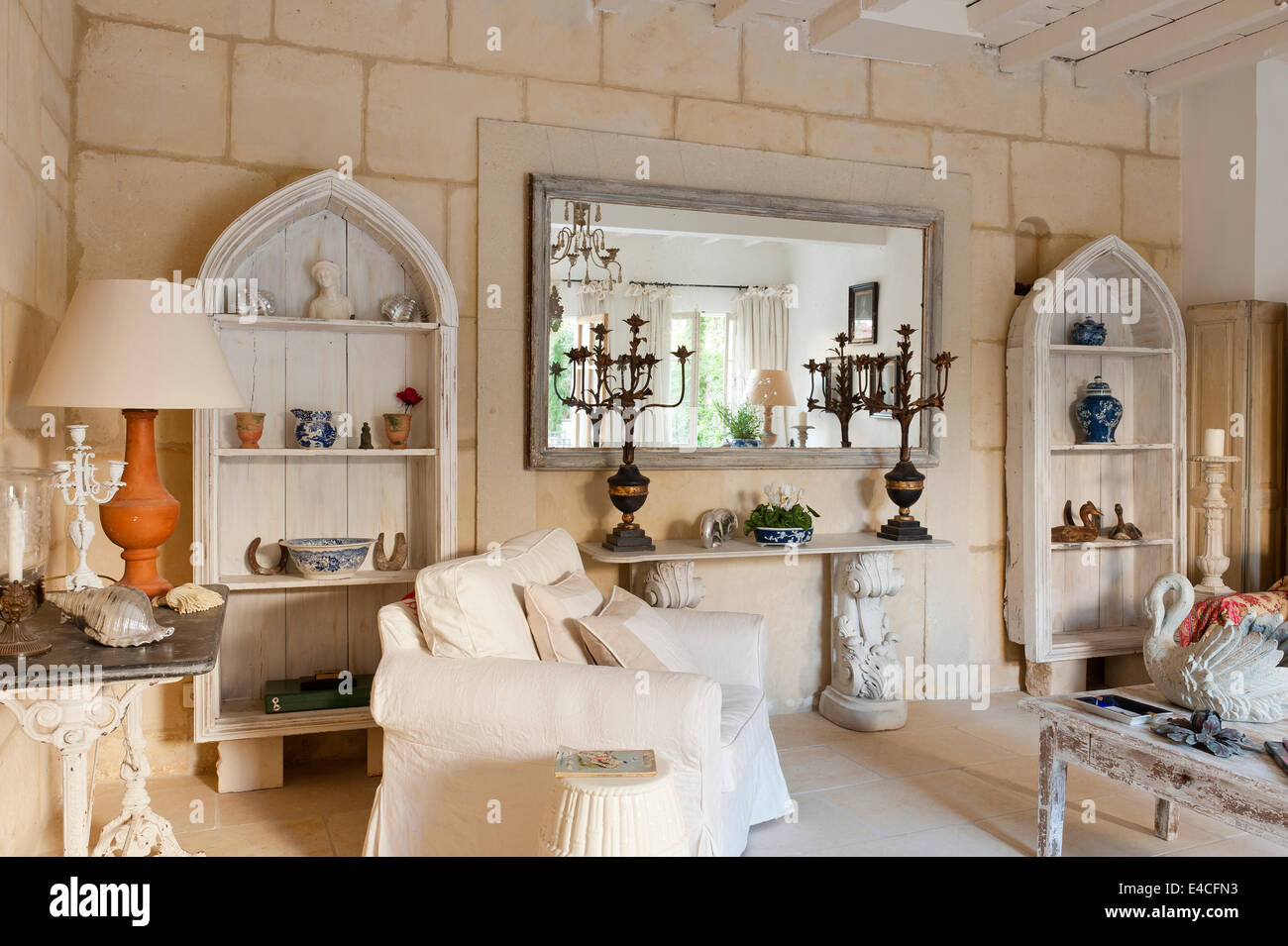 Pair of arched wooden shelves in sitting room with acanthus legged console table and candelabra. The walls are limestone blocks Stock Photo