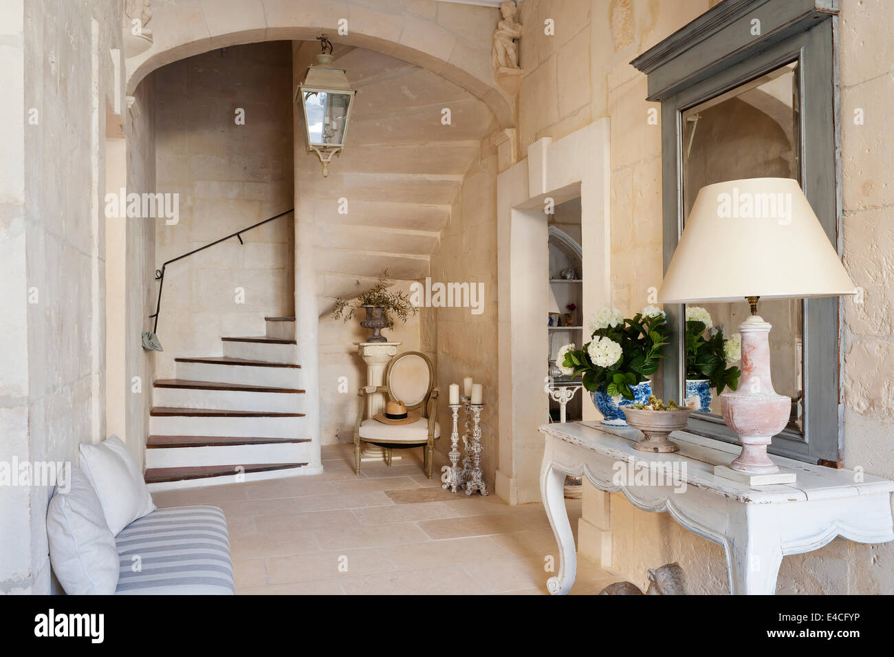 Entrance hall in 18th century provencal house with stone staircase and antique two legged wooden console table Stock Photo