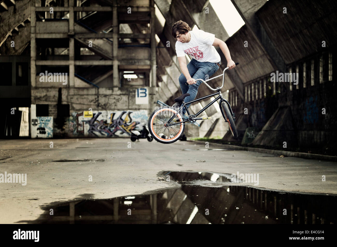 BMX biker performing a stunt over a puddle Stock Photo