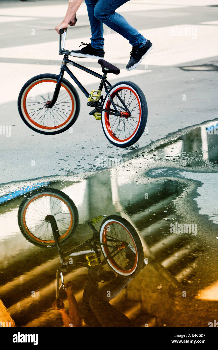 Reflections in a puddle of BMX biker performing a stunt Stock Photo