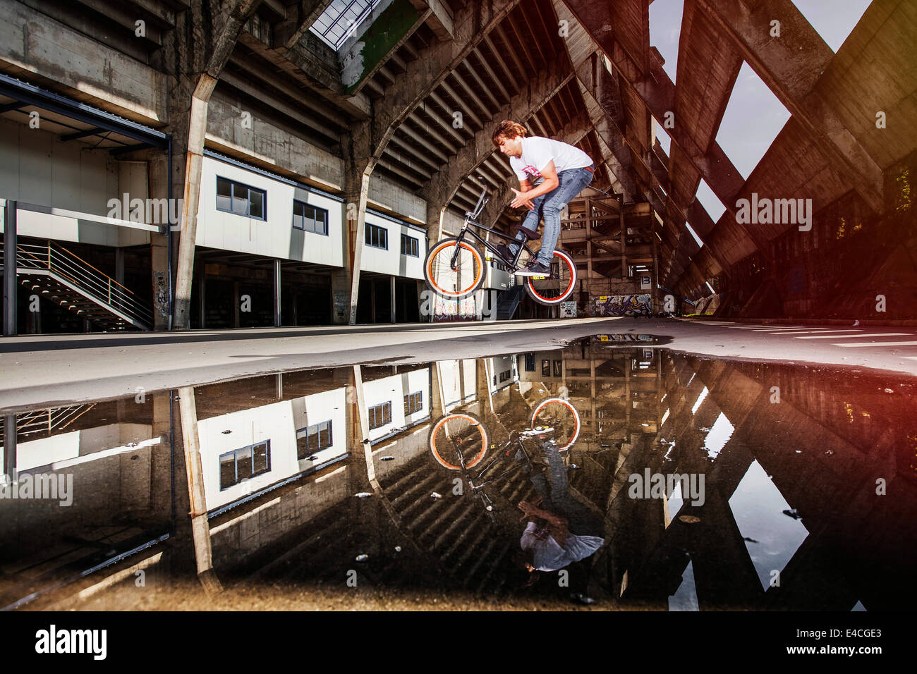 BMX biker performing a stunt over a puddle Stock Photo