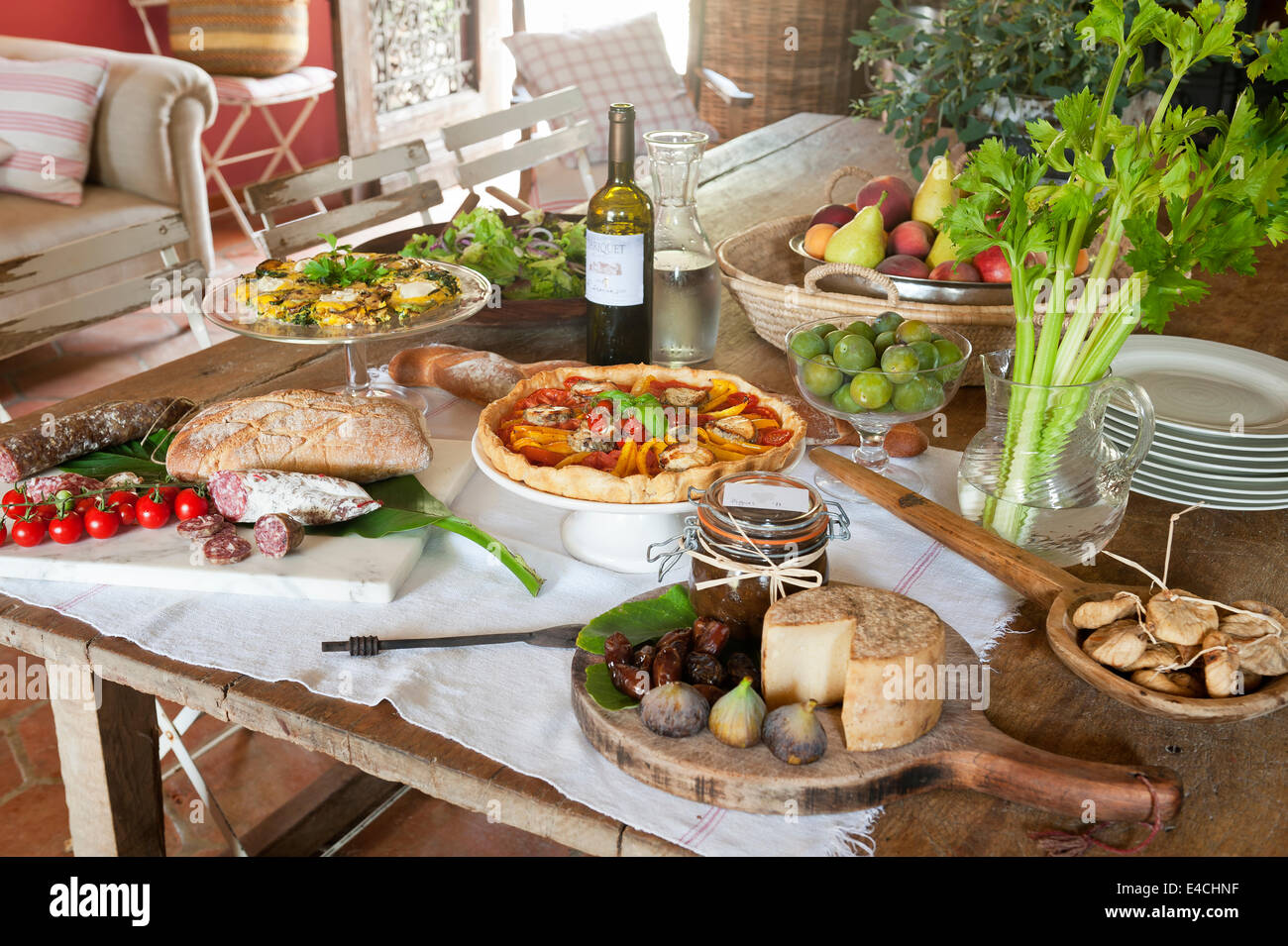 Table laid with assorted picnic foods - cheese, salami, tart, fruit and wine Stock Photo