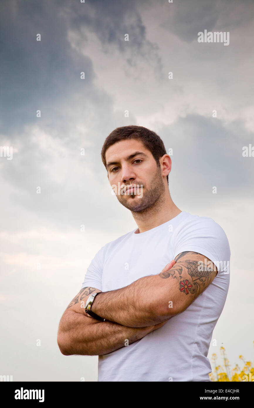 Young man with tattoo standing arms crossed, Tuscany, Italy Stock Photo