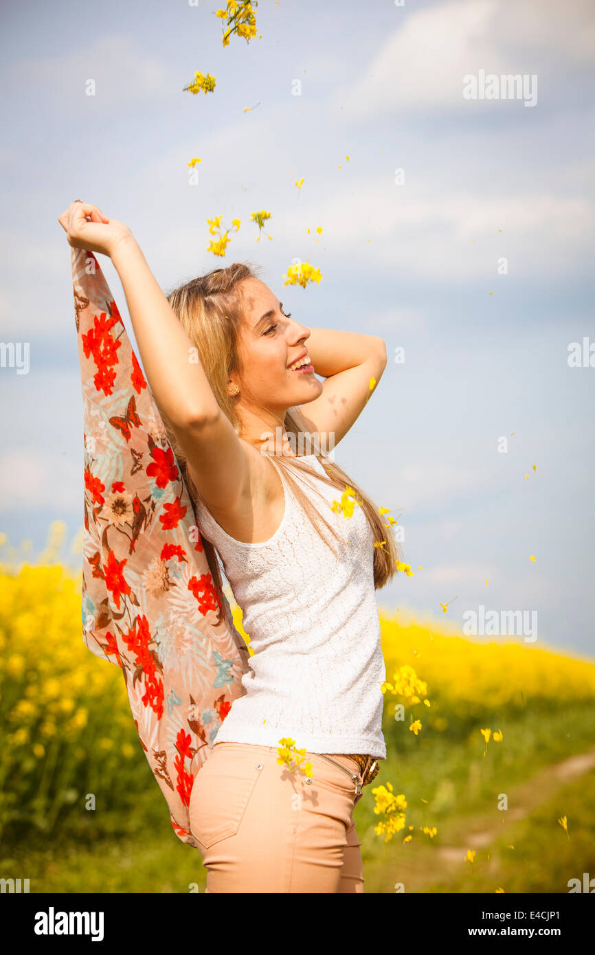 Young woman throwing colza flowers, Tuscany, Italy Stock Photo