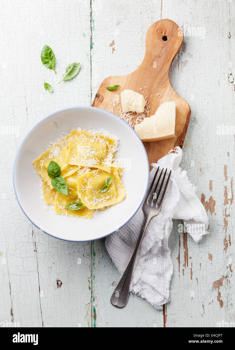 Ravioli pasta with cream sauce, basil and parmesan cheese on olive wood cutting board Stock Photo