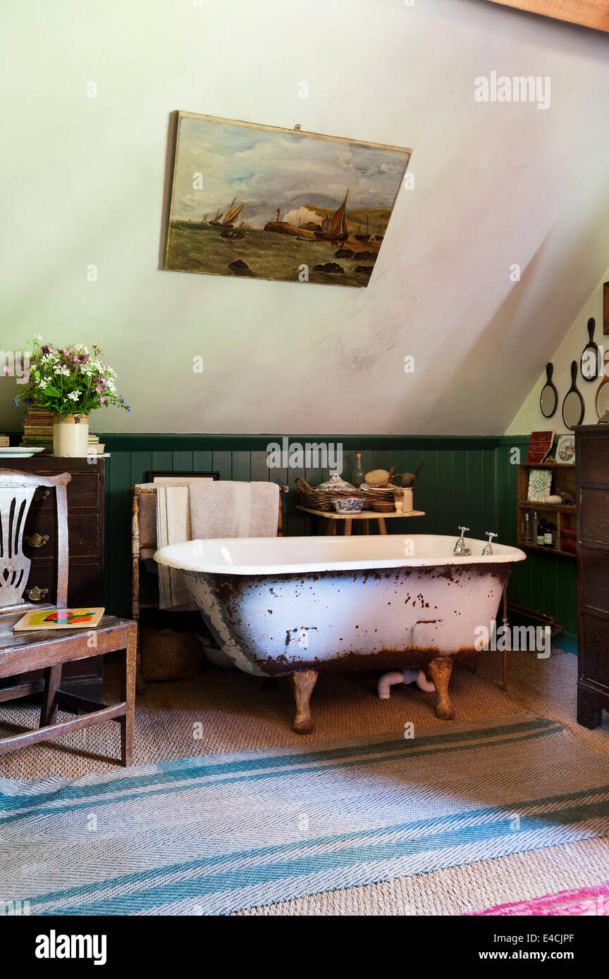 Cast iron free standing bath in room with seagrass carpet and George III country oak chair Stock Photo