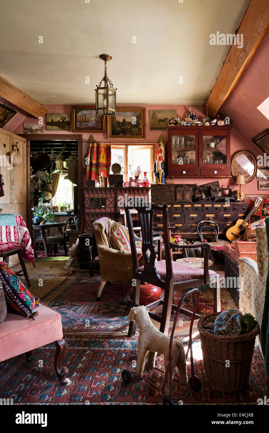 Cluttered cottage living room full of antique furniuture, artwork, old toys and vintage textiles Stock Photo