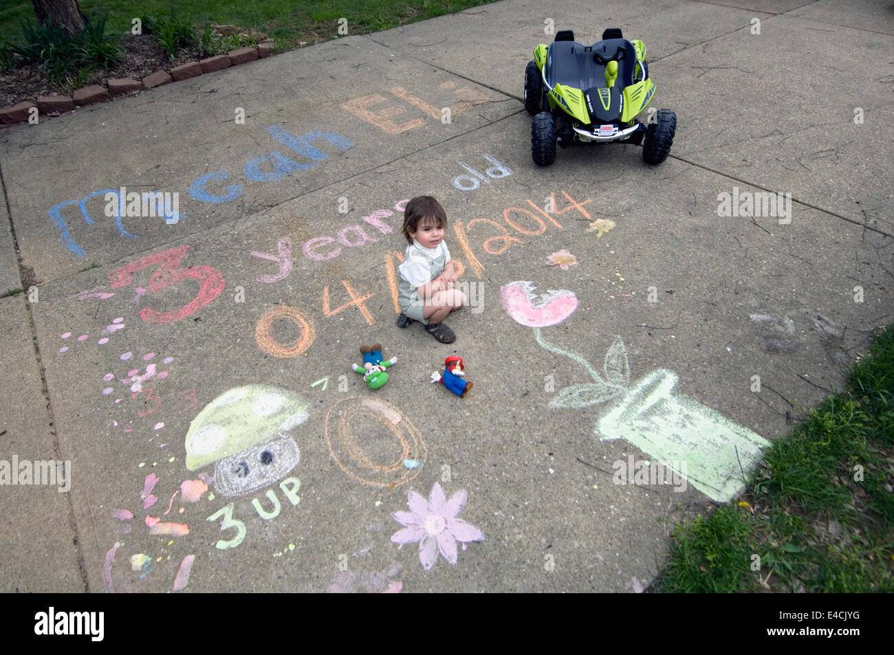 Three Year Old Boy With Sidewalk Chalk Depicting His Second Birthday Stock Photo