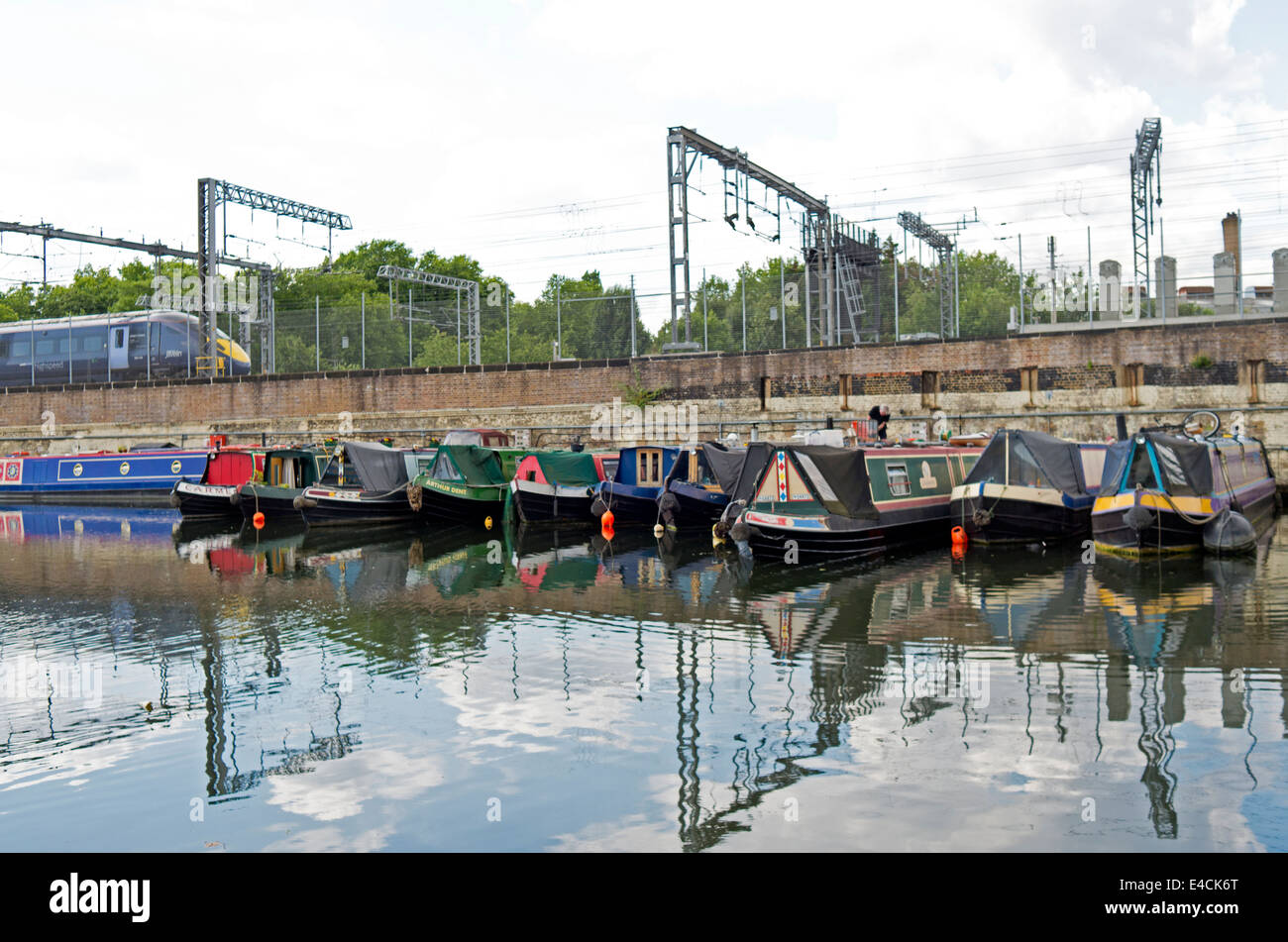 A Eurostar train passes above canal boats moored in the Regent's Canal in King's Cross, London. Stock Photo