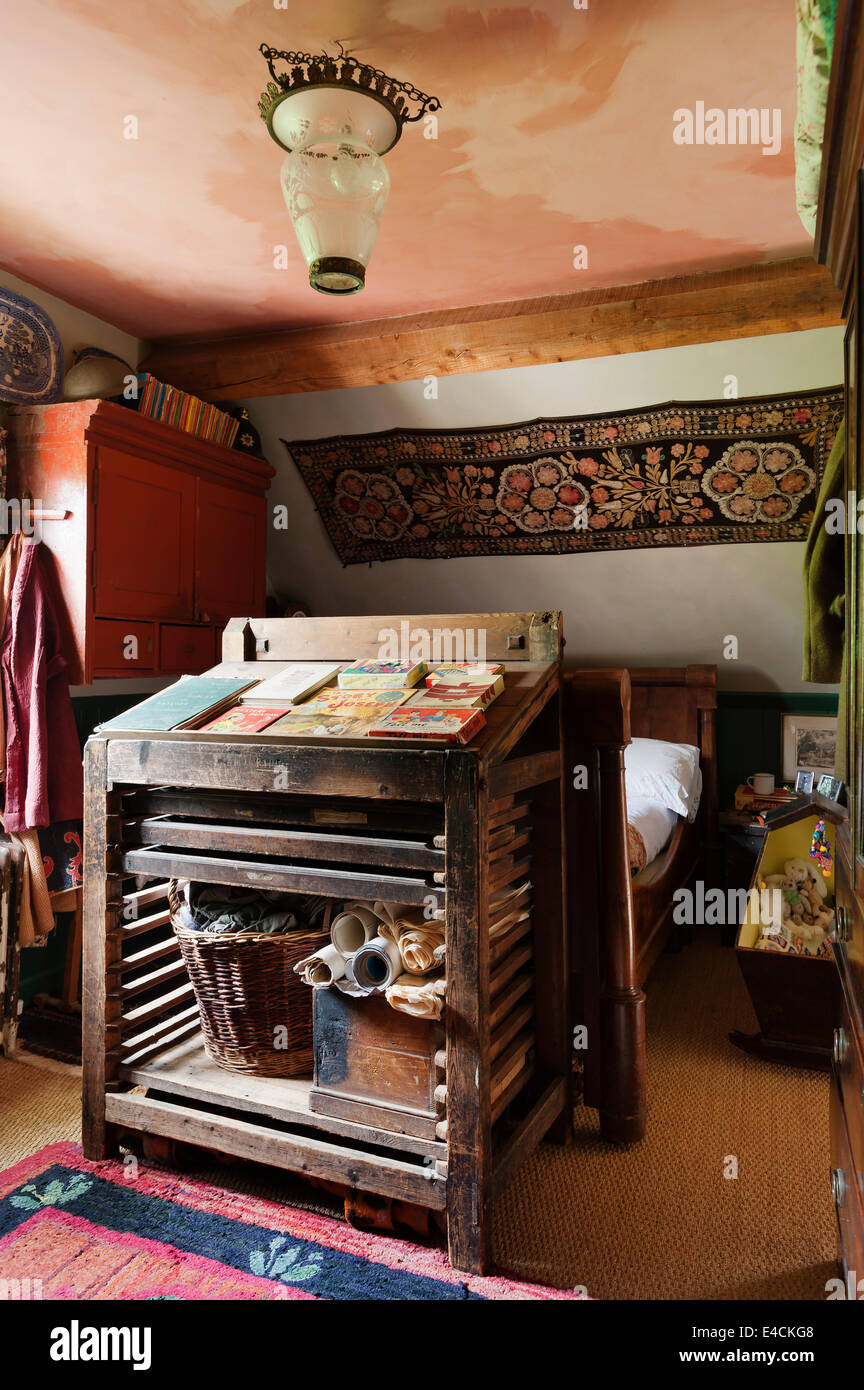 An Uzbeki Suzani textile hangs above a French empire bed in cottage bedroom with antique wooden frame rack Stock Photo