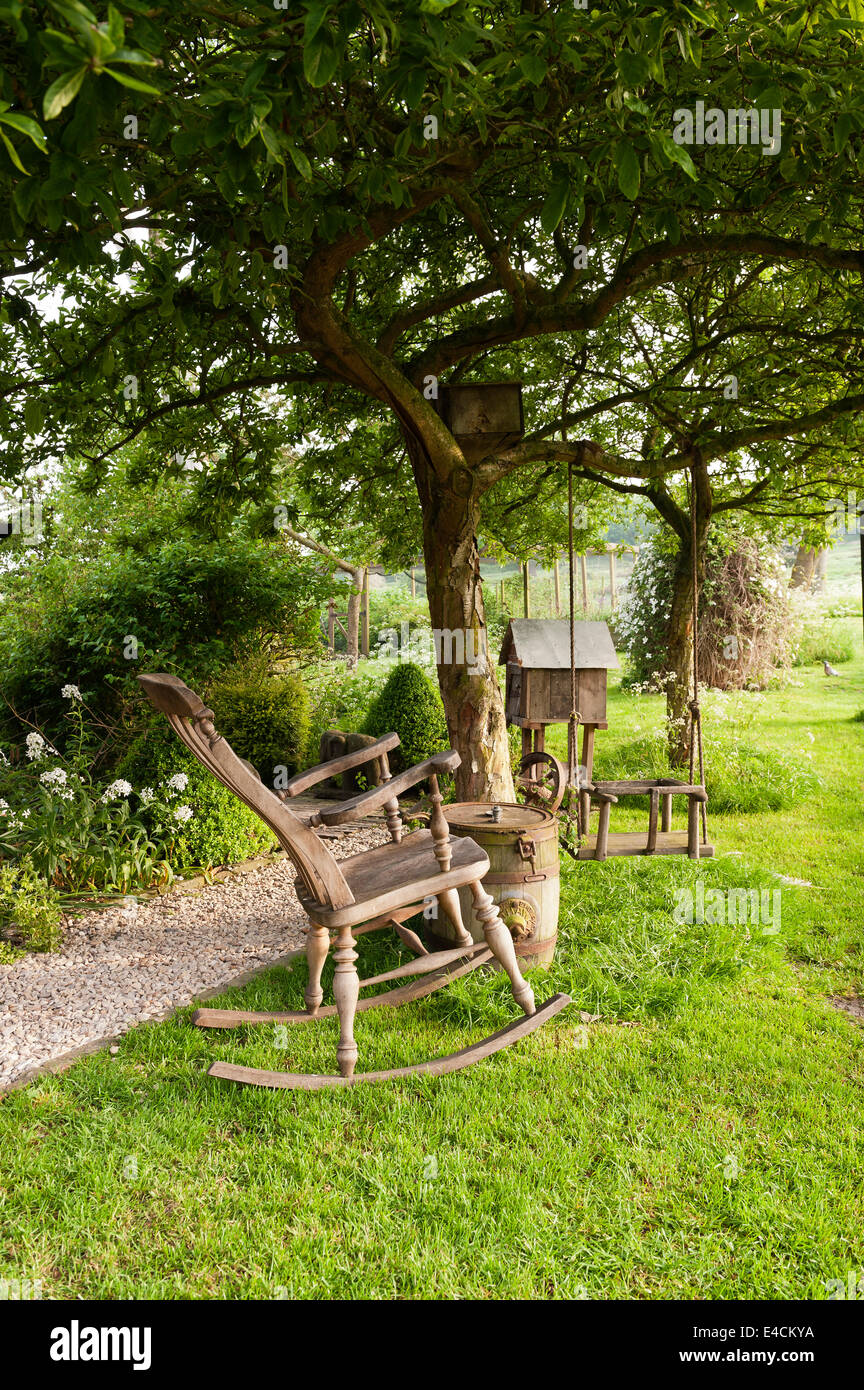 Wooden rocking chair and swing in garden of country cottage Stock