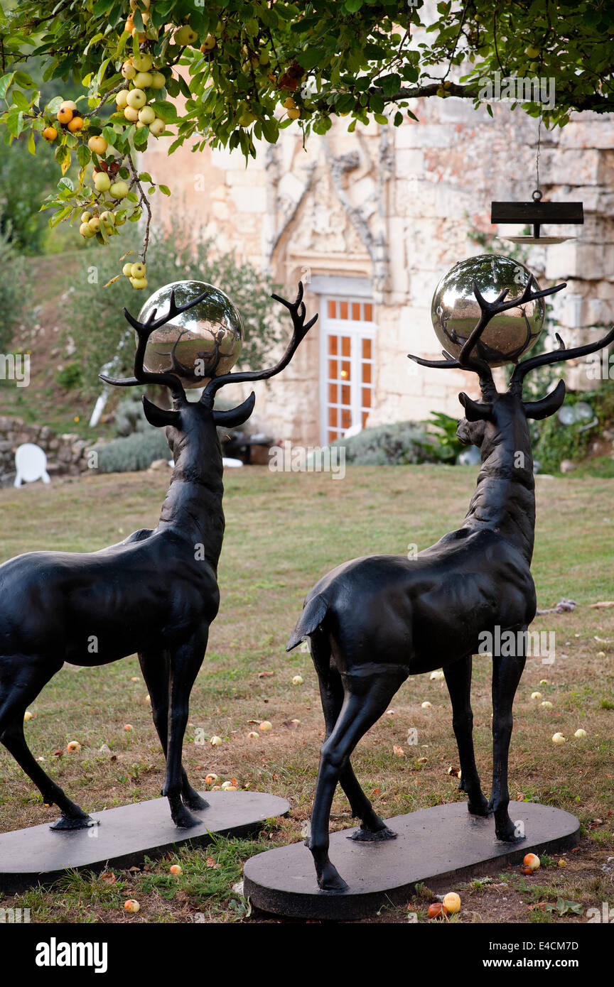A pair of bronze stags with silver balls between their antlers in garden under an apple tree. Stock Photo