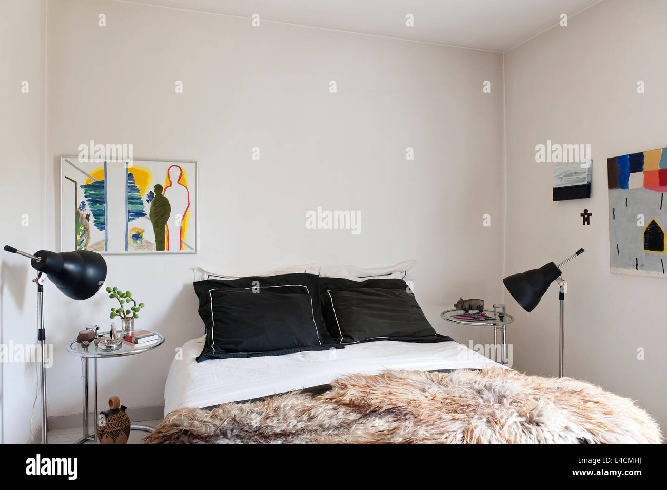 Double bed with sheepskin flanked by pair of Eileen Gray side tables Stock Photo