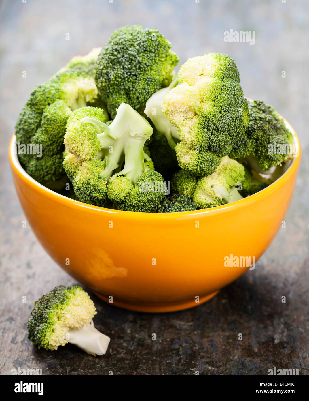 Bunch of fresh green broccoli in yellow bowl over wooden background - healthy or vegetarian food concept Stock Photo