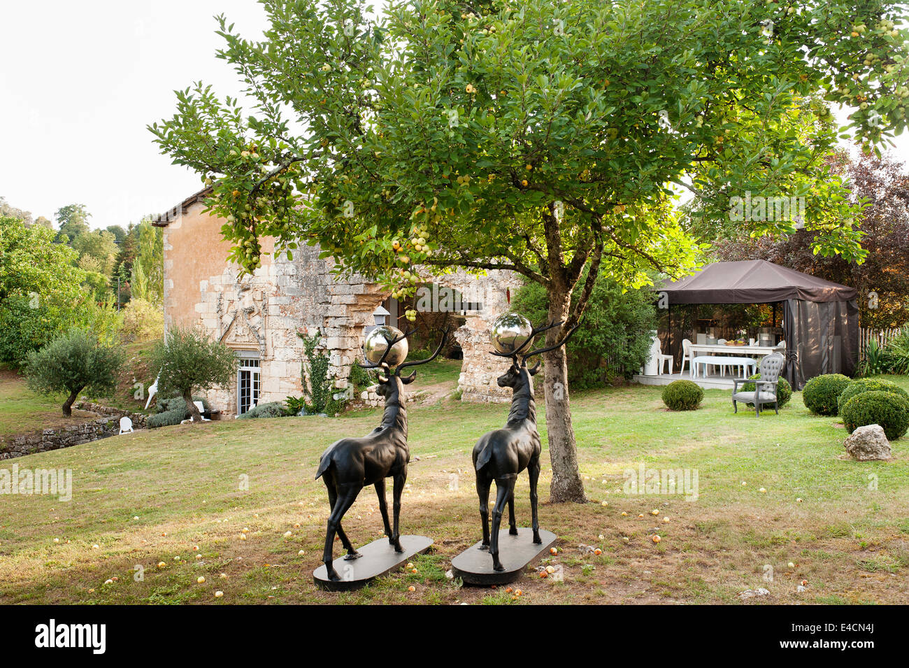 A pair of bronze stags under an apple tree in garden of 11th century french chapel Stock Photo