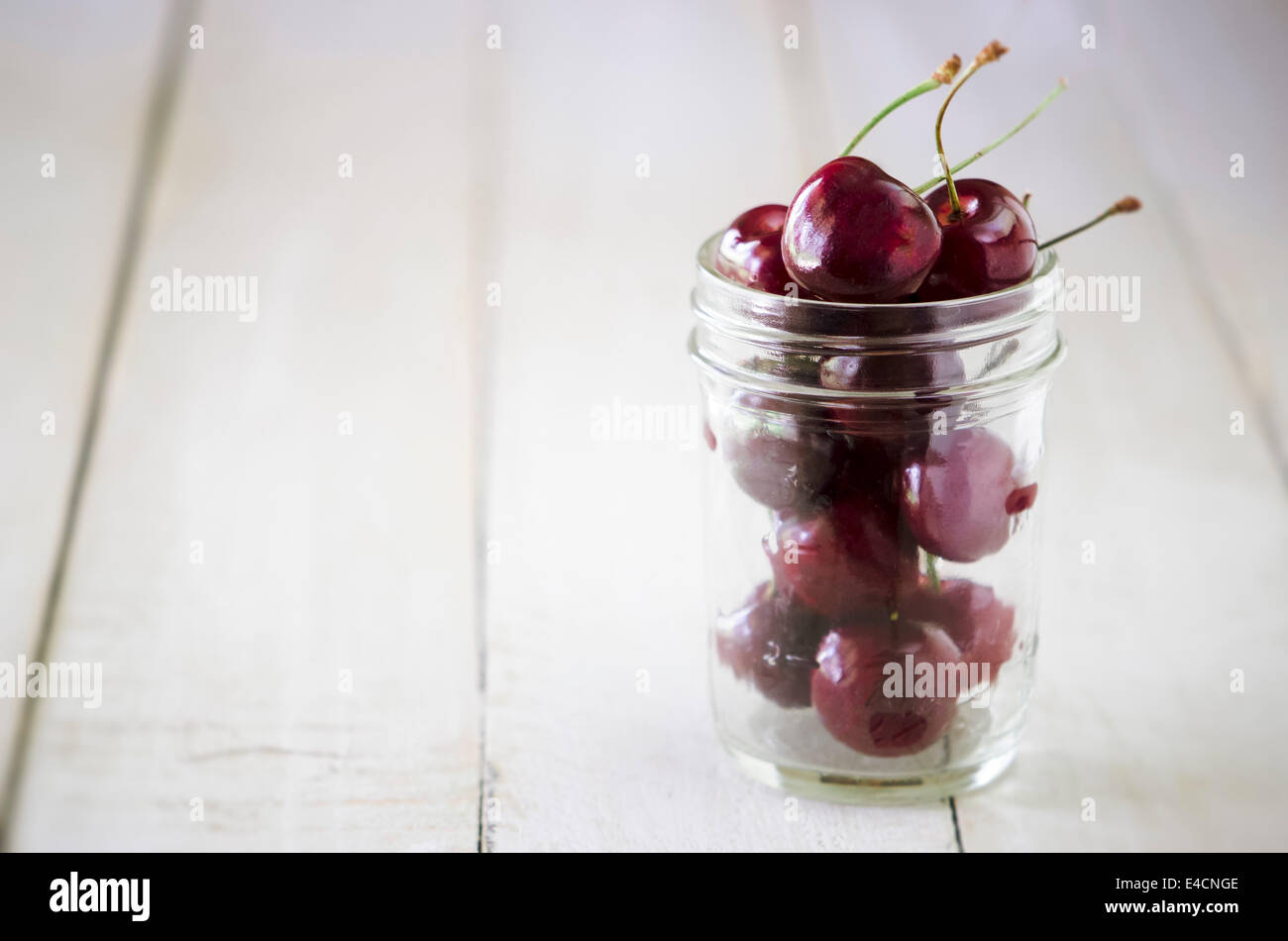 Cherries in a jar on a white wooden board Stock Photo Alamy