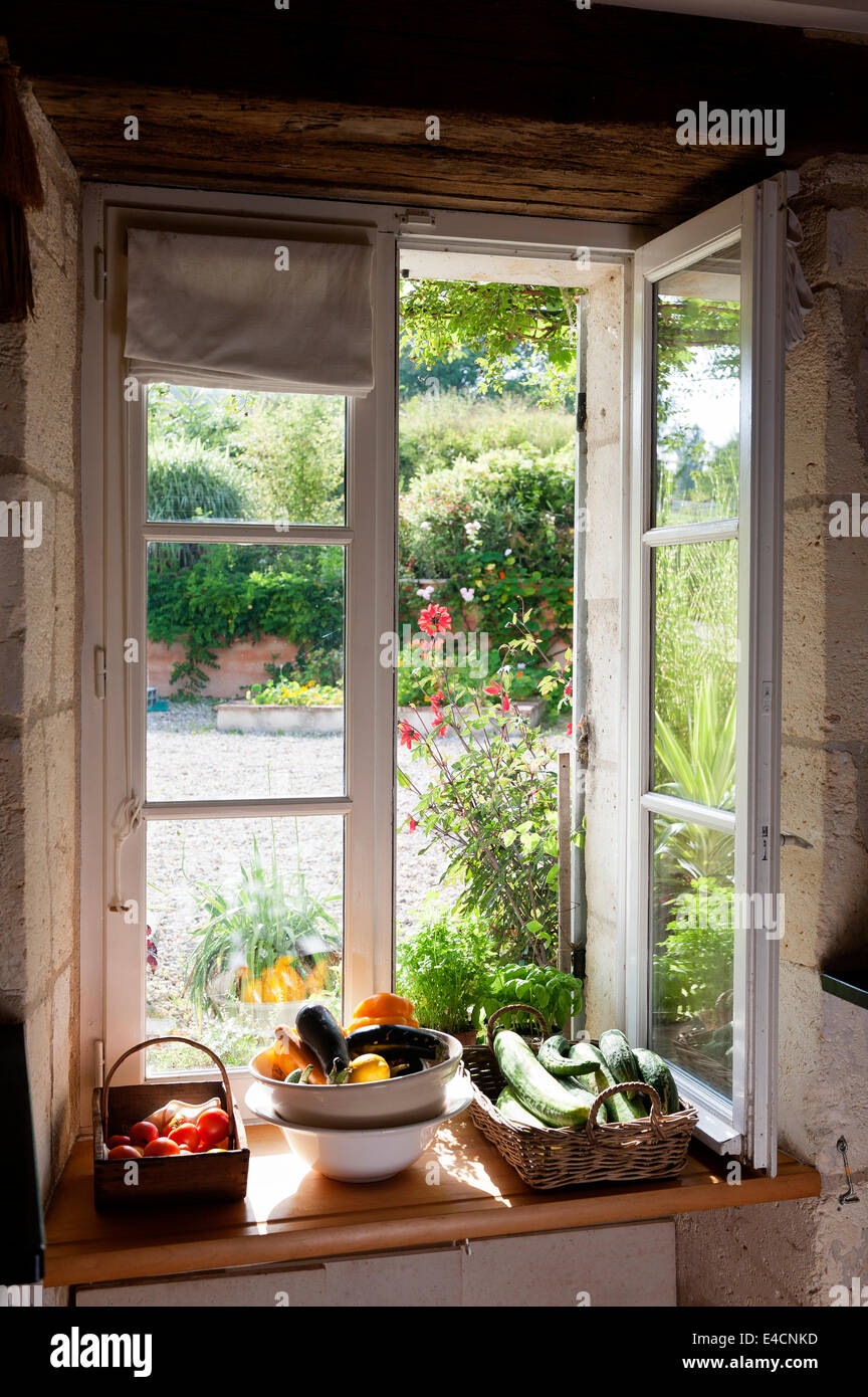 Fresh vegetables arranged in baskets on the sill of an open window set into thick stone walls Stock Photo