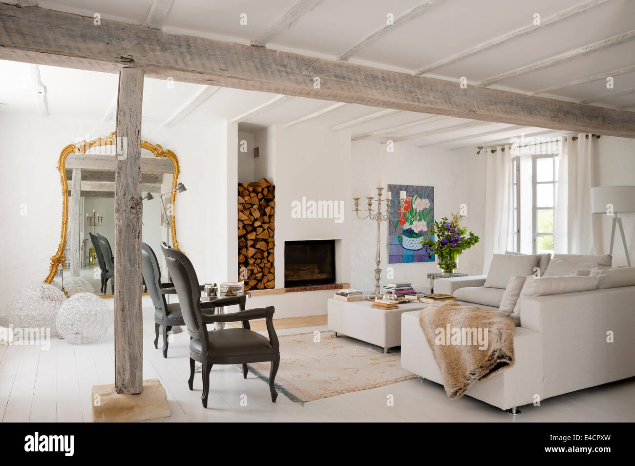Pair of Louis XV armchairs designed by Pieter Jamart in white open plan living space with oversized gilt framed mirror and sofas Stock Photo