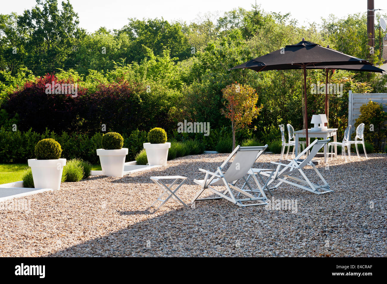 Deck chairs and parasols on gravel terrace Stock Photo