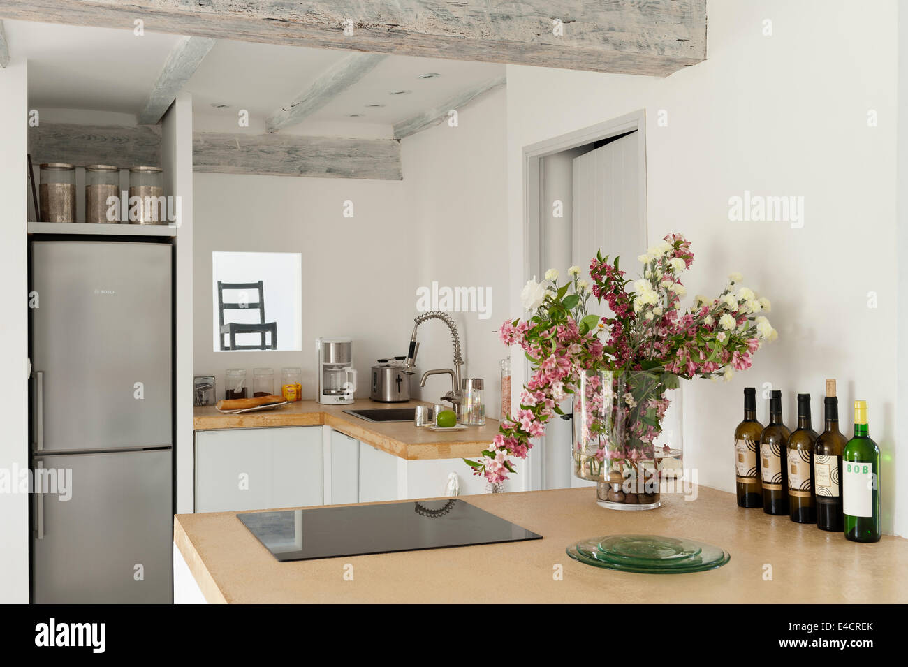 Yellow sand coloured concrete work surfaces in kitchen with vase of