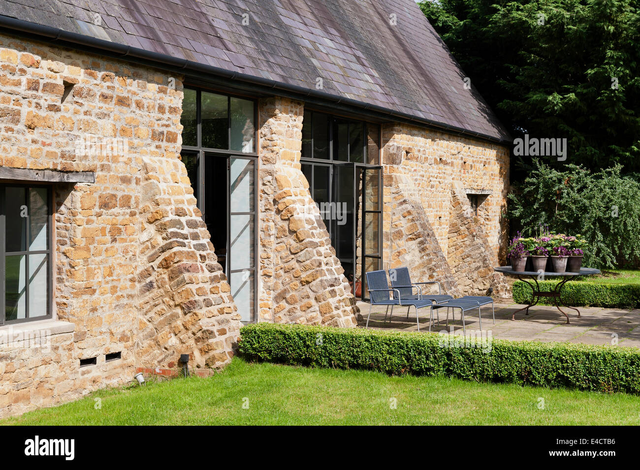 Exterior facade of a renovated Oxfordshire barn with terrace and box hedge Stock Photo