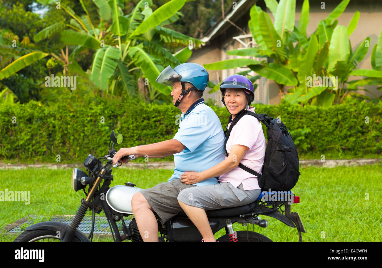 asian senior couple driving motorcycle to travel Stock Photo